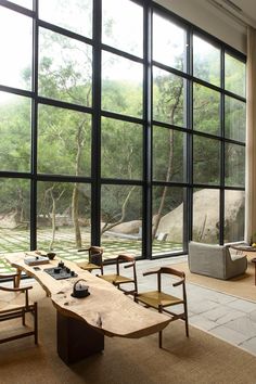 an instagram photo of a table and chairs in front of large windows with trees outside