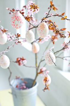 an easter tree with eggs on it in a vase next to a window sill