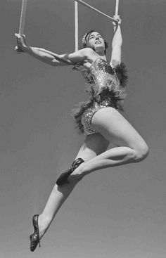 an old photo of a woman doing aerial acrobatics on a pole in the air