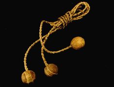 three wooden beads are tied together on a black background, with twine and rope