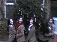 four girls standing in front of a christmas tree