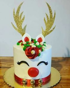 a white cake with gold glitter antlers and flowers on top, sitting on a wooden table