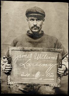 an old black and white photo of a man holding a sign with writing on it