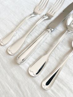 four forks, two spoons and one knife on a white tablecloth with silverware