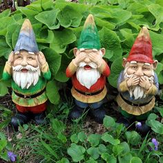 three garden gnomes are sitting in the grass