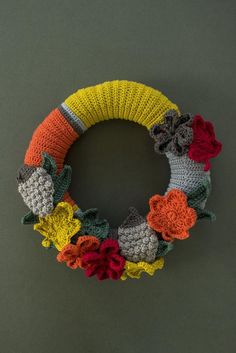 a crocheted wreath with flowers is hanging on the wall