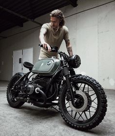 a man is sitting on a motorcycle in an empty garage with his hand on the handlebars