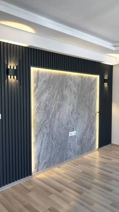 an empty room with wood flooring and black paneling on the walls, along with recessed lighting