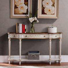 a white table with flowers and books on it in front of two framed pictures above it