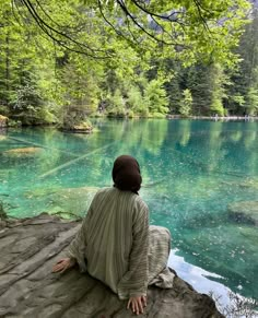 a person sitting on a rock looking at the water