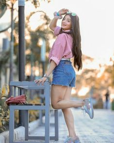 a young woman leaning on a bench posing for the camera