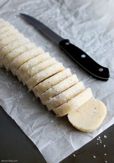 a sliced banana sitting on top of a piece of wax paper next to a knife