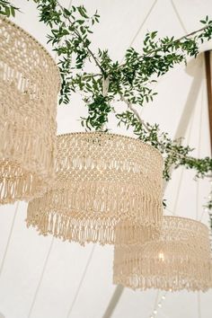 three chandeliers hanging from a ceiling with green leaves on them and one light fixture in the background