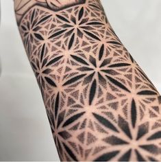 the arm is covered with black and white geometric tattoos on both sides of the arm