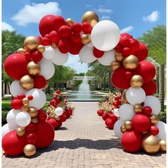 a red and white arch decorated with gold and white balloons for an outdoor wedding ceremony