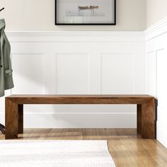 a wooden bench sitting on top of a hard wood floor next to a coat rack