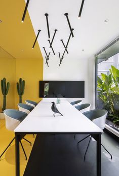 a long table with chairs and plants in front of a wall mounted planter on the ceiling