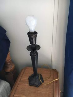 a lamp that is sitting on top of a wooden table next to a blue curtain