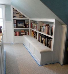 an attic bedroom with bookshelves and built - in seating for the guests to sit on