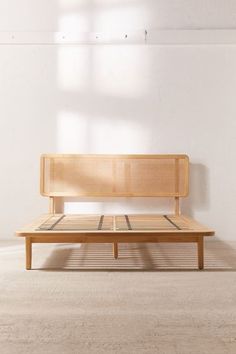 a wooden bench sitting on top of a white floor next to a wall with a window