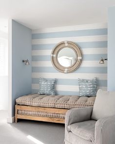 a living room with blue and white stripes on the walls, a couch and mirror