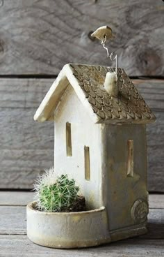 a small house shaped planter with a cactus in it