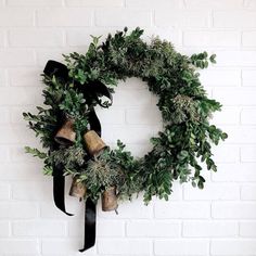 a wreath with bells and greenery on a white brick wall