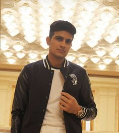 a man standing in front of a chandelier wearing a black jacket and white shirt