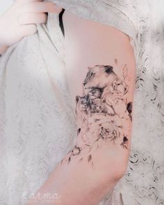 a woman's arm with flowers on it and a cat in the middle of her arm