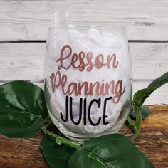 a wine glass with the words lesson planning juice on it next to some green leaves