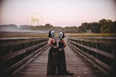 two women wearing masks standing on a bridge