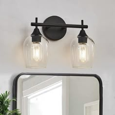 a bathroom vanity with two lights and a mirror on the wall next to it,