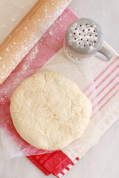 a doughnut sitting on top of a red napkin next to a rolling pin and grater