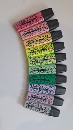 several different colored pens are lined up in a row on a white surface with black writing