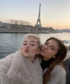 two women are kissing in front of the eiffel tower