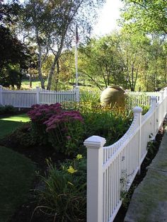 a white picket fence surrounded by flowers and trees