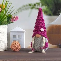 a small gnome figurine sitting on top of a table next to a potted plant