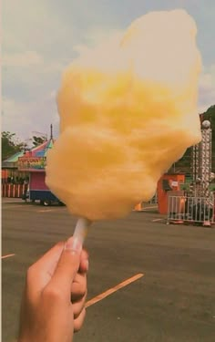 a person is holding a yellow cotton candy