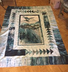 a quilt on the floor with an eagle flying over it