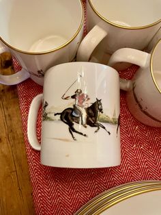 there is a coffee cup with a horse and rider on it next to other cups