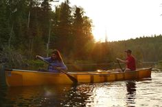 two people in a yellow canoe paddling on the water with trees in the background