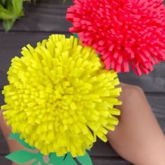 two red and yellow flowers sitting on top of a wooden table next to each other