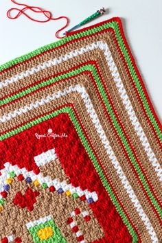 a crocheted christmas stocking is laying next to a pair of knitting needles