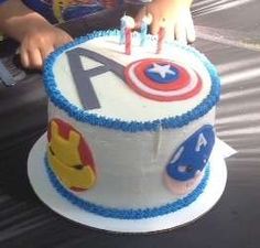 a child is cutting into a birthday cake decorated with captain america symbols and the letter a