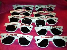 six pairs of sunglasses with names on them sitting on a pink cloth covered tablecloth