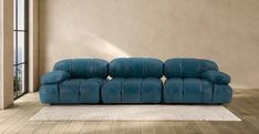 a blue couch sitting on top of a hard wood floor next to a large window