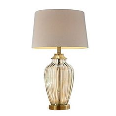 a glass lamp with a beige shade on it's base and a white lampshade