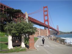 a man is walking down the street by the water and bridge in san francisco, california