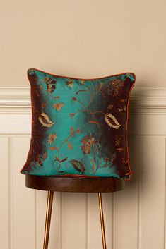 a blue pillow sitting on top of a wooden table next to a wall with white paneling