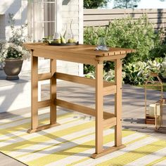 a wooden table sitting on top of a patio next to a potted planter